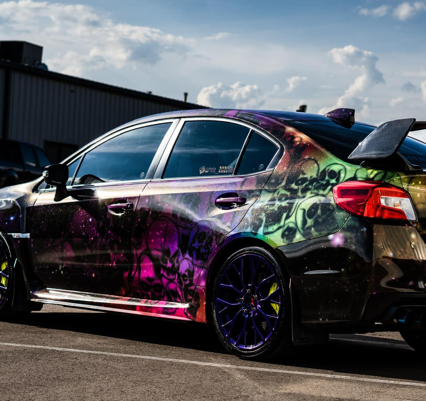 Custom Subaru with vibrant vinyl wrap featuring skulls and cosmic design, showcasing unique style and detailing.