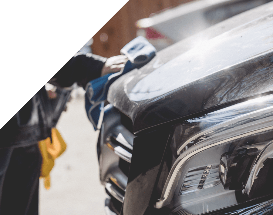 Person detailing a vehicle's hood with a microfiber cloth, showcasing professional auto detailing services at Luxe Auto Salon.